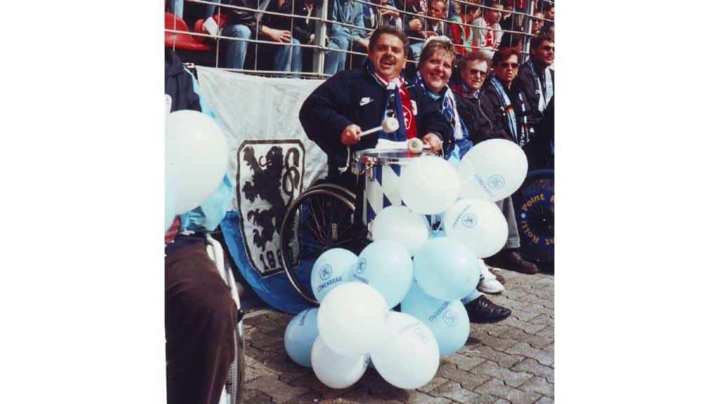 Bild vom Fanclubmitglied im Rollstuhl am Spielrand mit vielen blauen Luftballons um sich